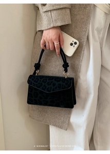 Close-up of black leopard print suede handbag with cylindrical knotted handle