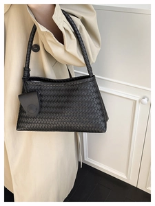 Detail shot of black woven leather handbag showing intricate grid texture and handle