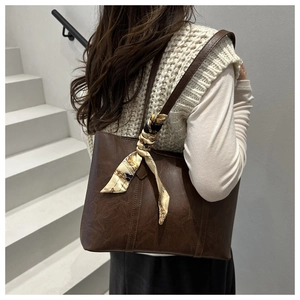 Detail of dark coffee tote bag with lychee texture and silk scarf accessory on strap