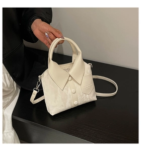 Close-up of cream shirt-shaped handbag with lapel, buttons and adjustable strap details