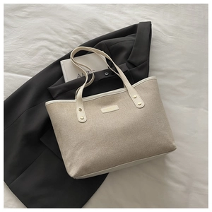 Detail of canvas tote bag with metal rivets and leather straps on stylish office backdrop