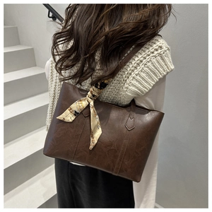 Side view of dark brown leather tote bag with silk scarf accent on shoulder strap
