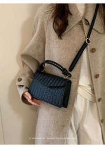 Detail of black woven crossbody bag texture with V-pattern and elegant vintage handle