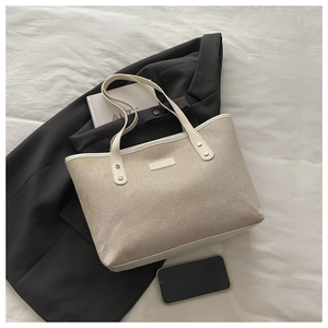 Detail of cream canvas tote bag with gold rivets on black blazer professional backdrop