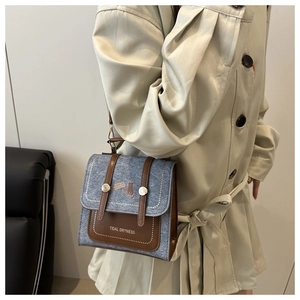 Detail of vintage square crossbody bag with cat illustration and gold buckle accents