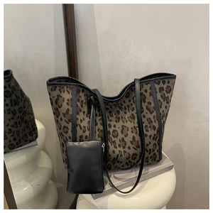 Detail of leopard print tote bag with black trim and a matching hanging leather charm pouch