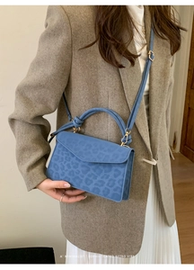 Blue leopard print retro square bag shown as a crossbody on a grey wool blazer