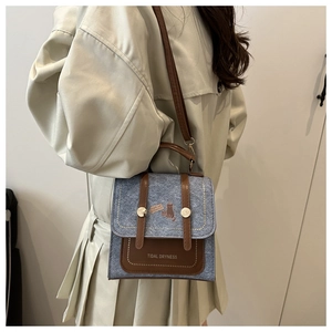 Detail of blue felt crossbody bag with brown leather accents and cute cat illustration