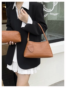 Brown woven leather shoulder bag and pouch set on a minimalist street background