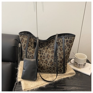 Detail of leopard print tote bag with black trim and matching small pouch on a table