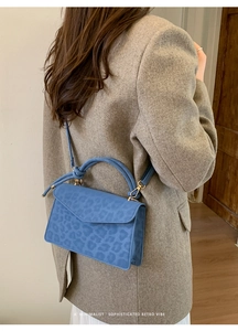 Detail of blue leopard print crossbody bag with gold hardware and circular handle