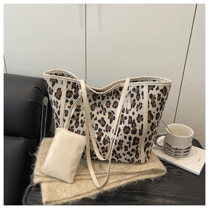 Close-up of leopard print tote bag featuring leather handles and matching zipper pouch
