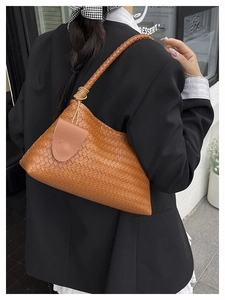 Detailed close-up of brown woven shoulder bag showing fine texture and knotted strap