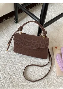 Close-up of leopard print crossbody bag with knotted handle and gold metal hardware