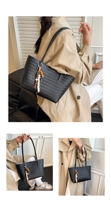 Detail of black woven tote bag with beaded tassel charm and slim shoulder straps