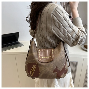 Dettaglio borsa tote in tela marrone con tracolla in pelle e toppa decorativa vintage