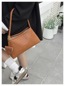 Detailed view of woven brown leather shoulder bag with matching braided handle design
