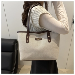Detail of canvas tote bag with brown leather trim and CAHRES & HEKA fashion logo label