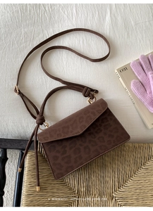 Top-down view of retro leopard print handbag on white fabric and woven stool