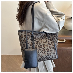 Leopard print tote bag with black shoulder strap and matching small pouch in lifestyle setting
