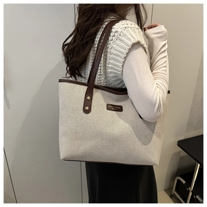 Detailed side view of off-white canvas tote bag with brown leather straps on a model