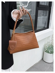 Close-up of brown woven leather handbag with matching small saddle-shaped pouch detail