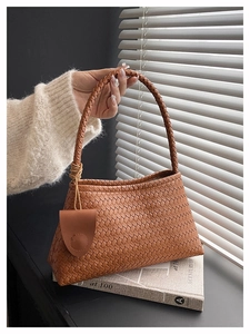 Detail of brown woven shoulder bag showing premium texture and leather charm accessory