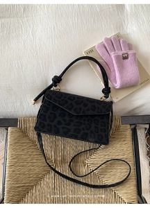 Top view of black leopard print suede crossbody bag with knot handle and gold hardware