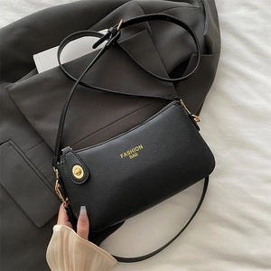 Classic black litchi pattern leather crossbody bag with gold hardware on a stylish suit