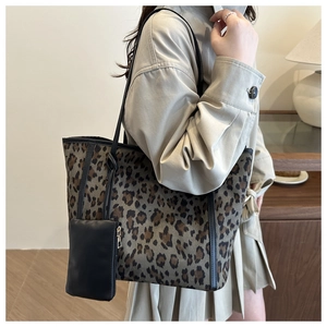 Detail of leopard print tote bag with black leather trim and small zipper pouch attachment