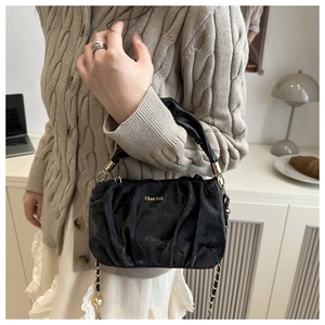 Détail du sac nuage plissé noir avec logo doré et chaîne élégante porté par un mannequin