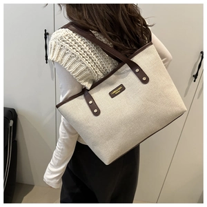 Detail of canvas tote bag with brown leather handles and CAIRES & BEKA branding