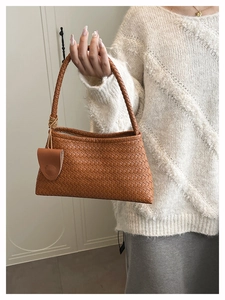 Close-up of caramel leather shoulder bag with intricate woven texture and matching charm