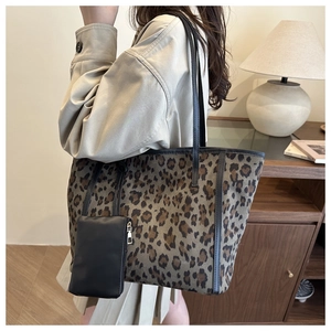 Detail of leopard print tote bag with black leather straps and hanging small pouch