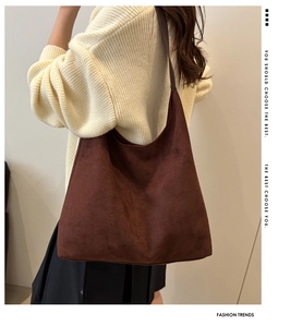 Close-up of brown suede hobo bag with wide strap styled on a woman's shoulder