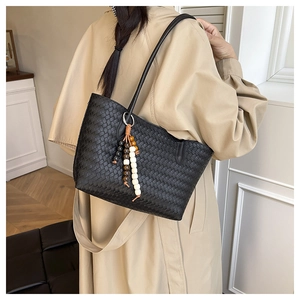 Detail of black woven checkerboard shoulder bag with colorful wooden bead tassel decoration