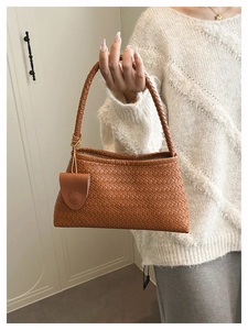 Brown woven tote bag detail showing classic cross-weave leather texture and charm