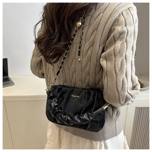 Détail du sac nuage plissé en velours noir avec chaîne dorée porté par un mannequin