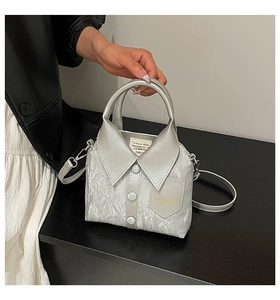 Detailed view of a silver shirt-shaped handbag with glossy finish and metal button accents