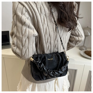 Détail du sac plissé noir avec bandoulière en chaîne dorée et logo imprimé
