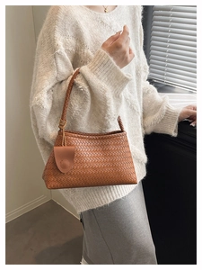 Close-up of brown woven leather hobo bag on model wearing cream knit sweater