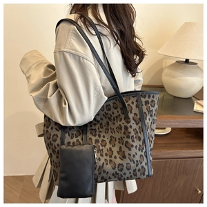 Leopard print tote bag detail showing black leather straps and mini hanging wallet pouch