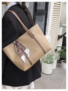 Detail einer beige Leder-Tote-Bag mit braunen Riemen und Herz-Print Schal-Dekoration