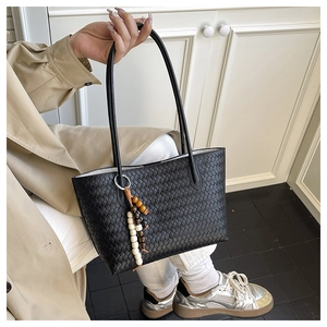 Close-up of black woven tote bag with ethnic style wooden beaded tassel pendant charm