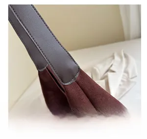Detail of burgundy suede tote bag showing neat stitching and brown leather strap