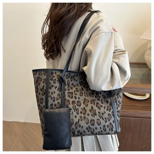 Leopard print tote bag with small black pouch worn by a model in a cozy indoor setting