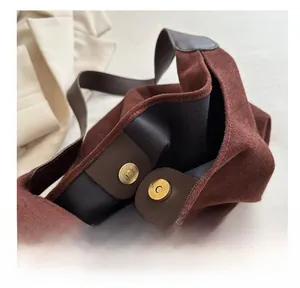 Close-up of golden magnetic clasp and premium suede texture on brown tote bag