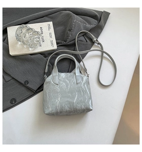 Detail shot of a silver metallic pleated handbag with adjustable thin shoulder strap