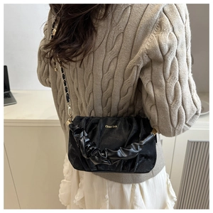 Détail du sac nuage froncé noir avec chaîne dorée et logo sur un pull en maille