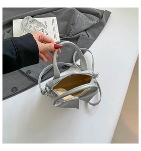 Interior view of silver mini bag with metallic texture, bow detail and zipper closure